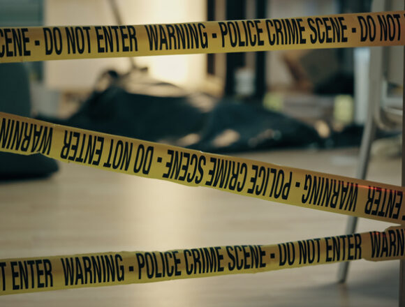 The body of a dead person lying on the floor covered with plastic corpse bag, murder scene secured by warning police tape Woman Found Dead in Delhi Hotel, Man Hospitalised After Apparent Suicide Attempt